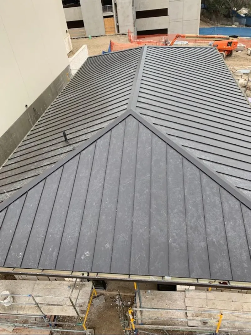 Commercial metal roof construction with crane equipment in Suncrest